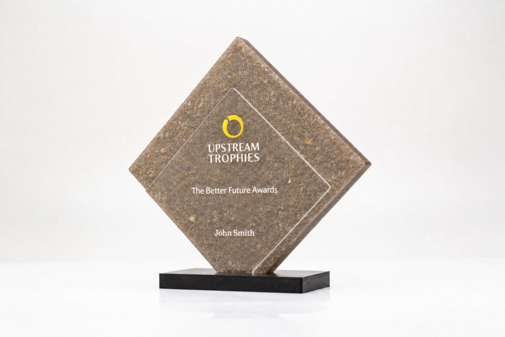 Ruitvormige trofee met goudstof middelpunt gemaakt van gerecyclede parfumdopjes op een zwarte sokkel